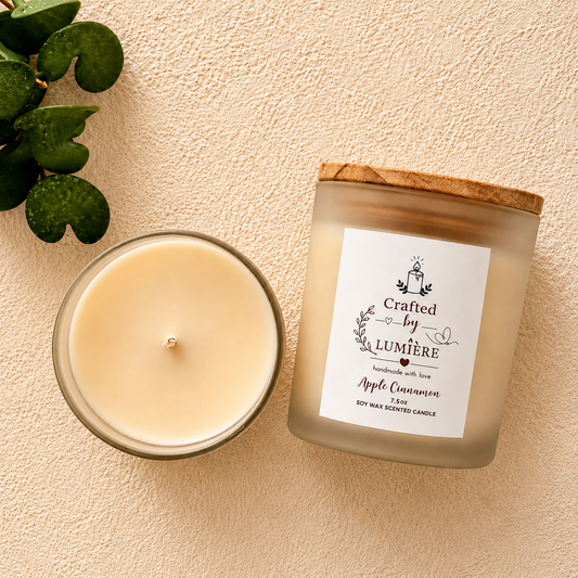 A frosted glass candle jar with a bamboo wood lid sits next to an open candle showing the cream-colored wax. The label reads 'Crafted by Lumière' and 'Apple Cinnamon'.